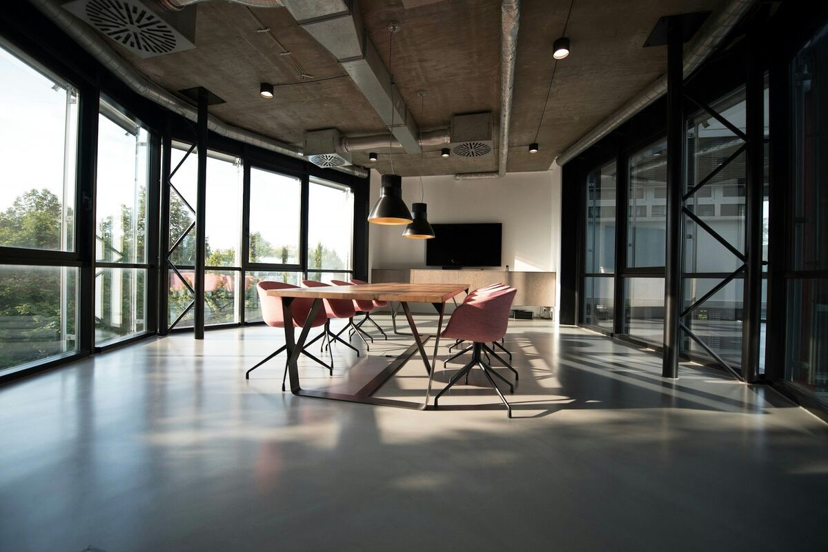 A bright workspace with a long table and tall windows